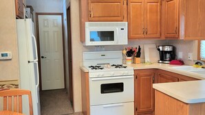 Una cocina compacta con armarios de madera, una estufa blanca, un microondas y un refrigerador.
