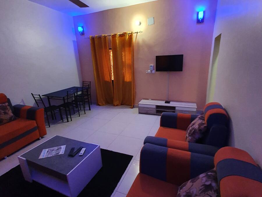 Een woonkamer met een bank, een salontafel, een televisie en een plafondventilator.