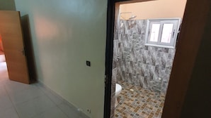 A bathroom with a shower, tiled floor, and a window. - Appartement meublé GOLF (Bamako)