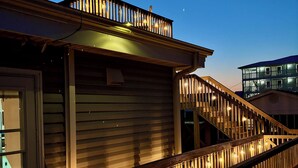 A wooden deck with railings, a staircase, and a building with a balcony. - Ocean View-Pet Friendly- 1min walk to beach-sleeps 6 (Surf City)