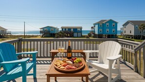 A deck with a table set for a meal, overlooking a beach with houses. - Ocean View-Pet Friendly- 1min walk to beach-sleeps 6 (Surf City)