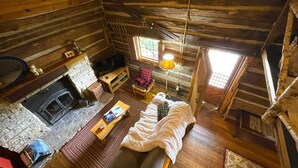 A cozy log cabin interior with a fireplace, wooden furniture, and a bed. - Historic Sadie's Log Cabin (McGregor)
