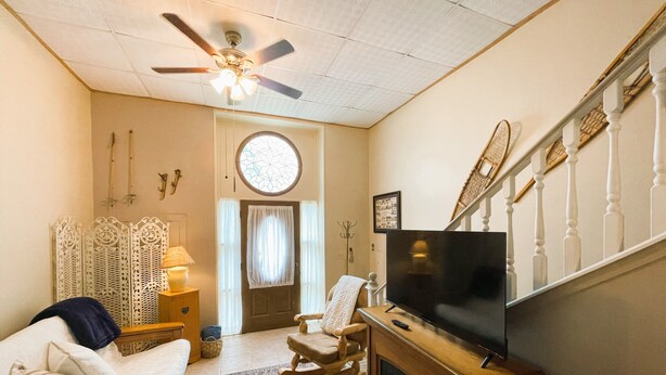 A living room with a ceiling fan, a fireplace, a television, and a rocking chair. - Cozy Alpine Retreat in Historic Downtown (McGregor)