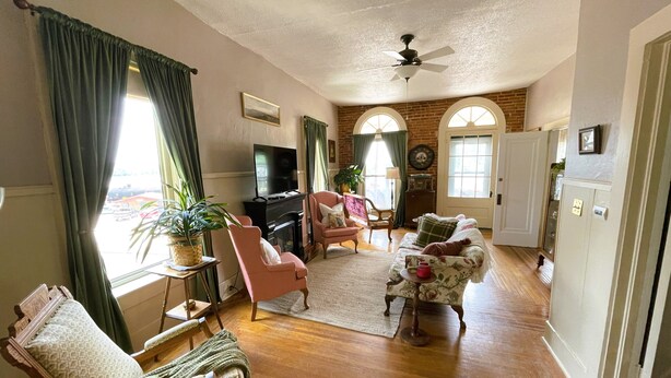 A living room with a fireplace, a television, and a ceiling fan.
