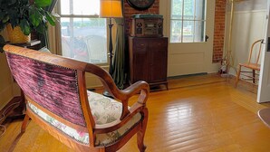A room with a wooden floor, a vintage chair, a lamp, a radio, and a door with a window.