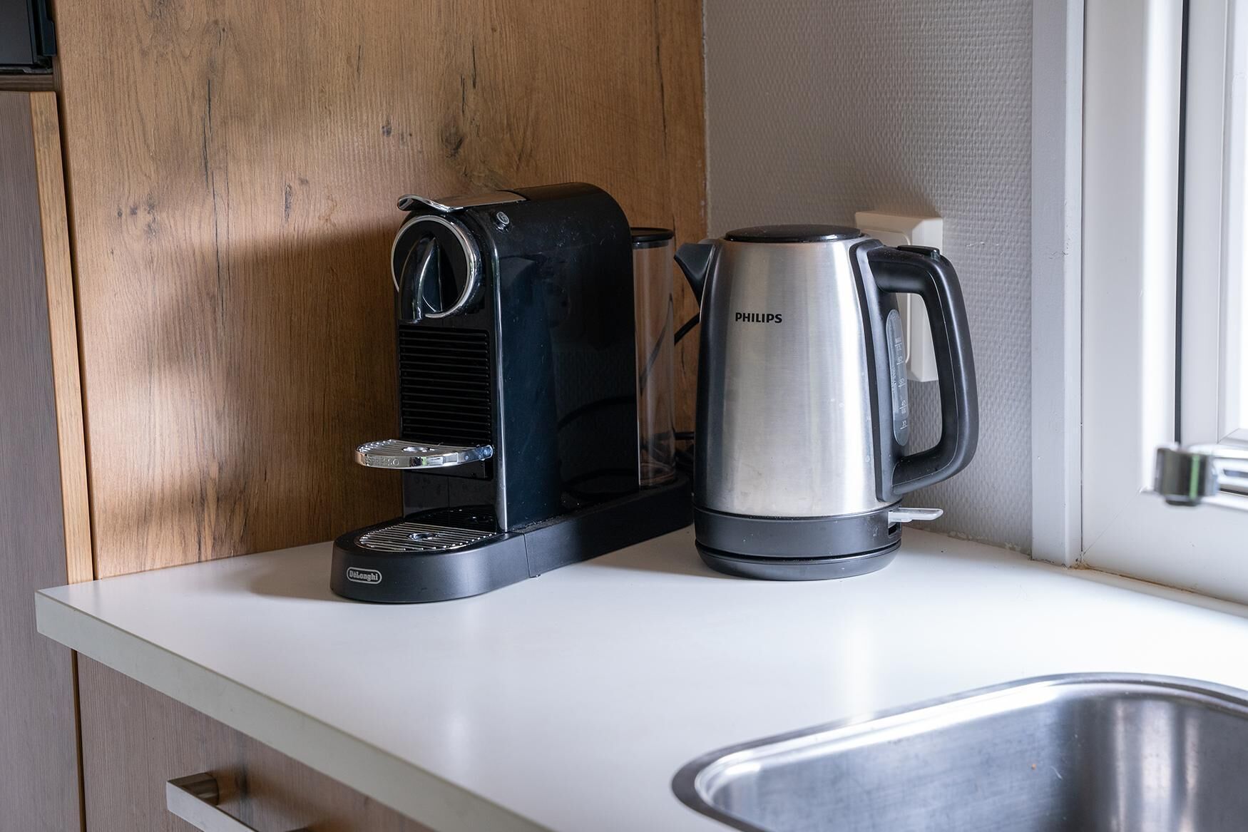 A kitchen with a coffee maker and a kettle on a white countertop.