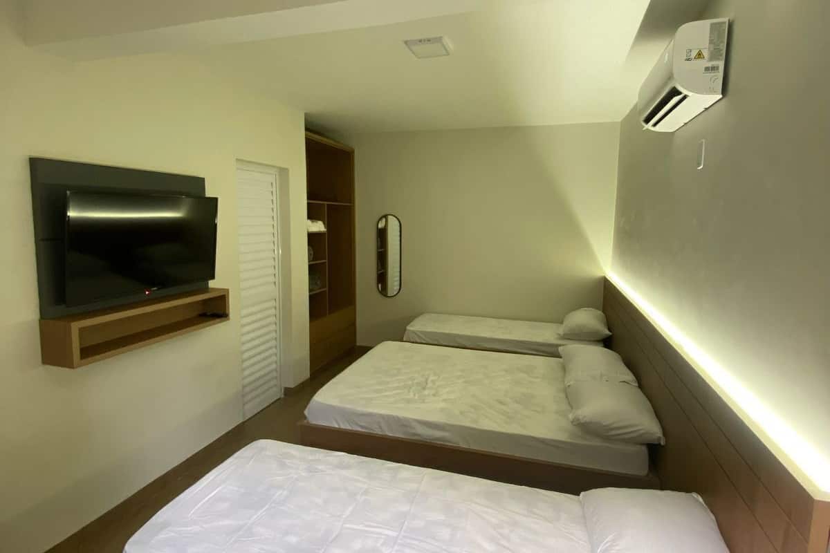A compact hotel room with two single beds, a TV mounted on the wall, and a small closet.