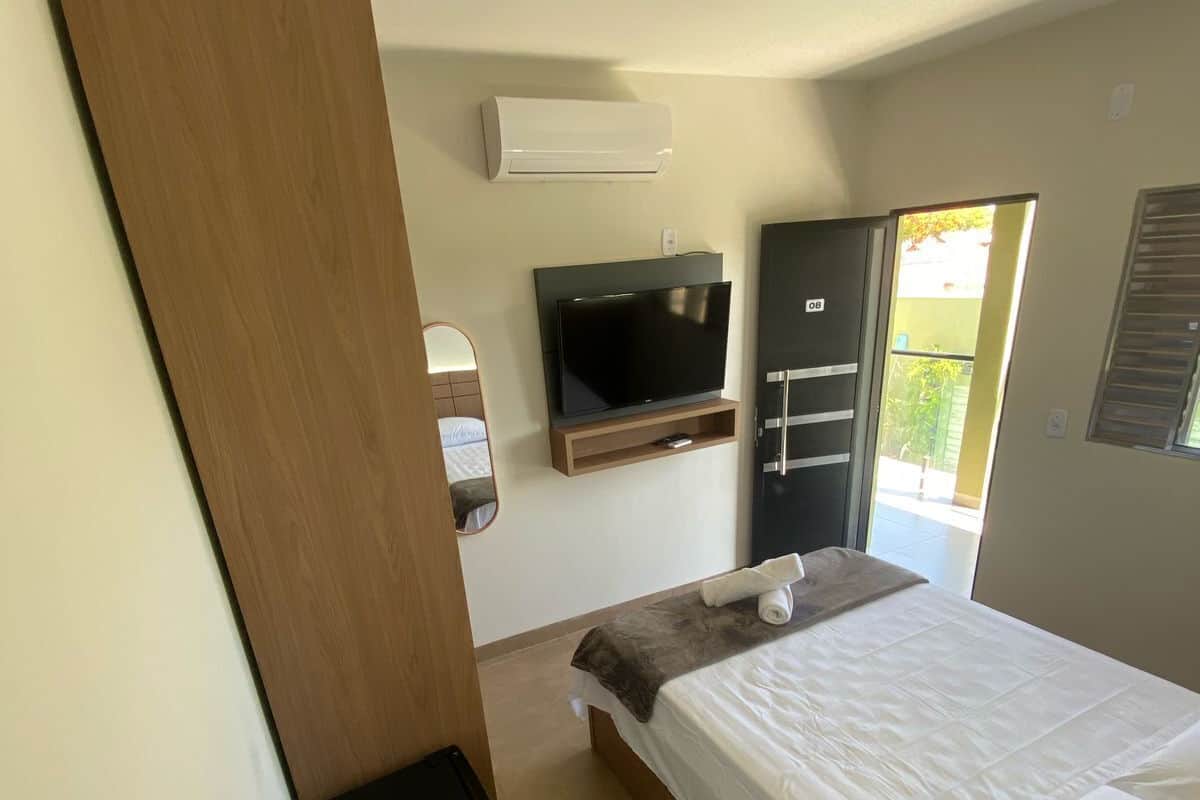 A bedroom with a bed, a TV, a wardrobe, and a small table.