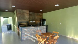 A spacious indoor area with a wooden dining table and chairs, a stone wall, and a refrigerator. - Pousada Capiau  (Bonito)