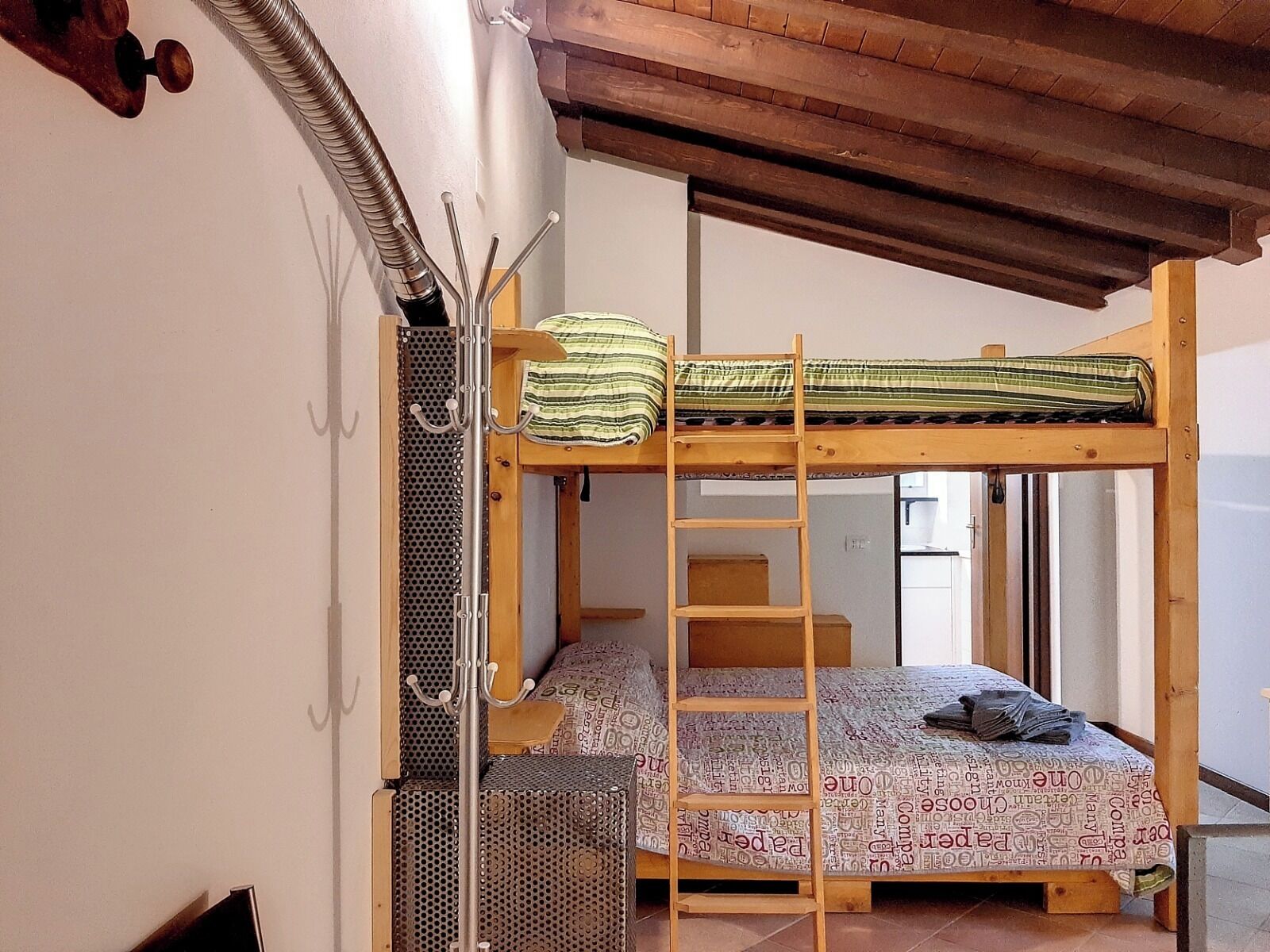 A bunk bed with a ladder, a metal rack, and a patterned bedspread.