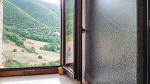 Ein Zimmer mit einer großen Glasdoor, die zu einer malerischen Aussicht auf eine hügelige Landschaft führt.