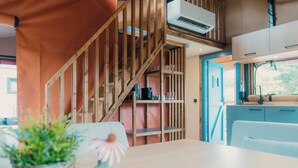 A kitchen with a wooden staircase, a dining table with a vase, and a view of the outdoors. - Wander Lodge | 5 persons (Voorthuizen)