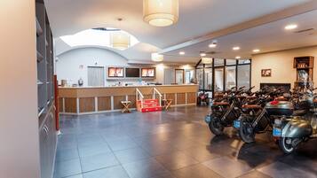 A spacious lobby with a reception desk, seating area, and a motorcycle parking area.