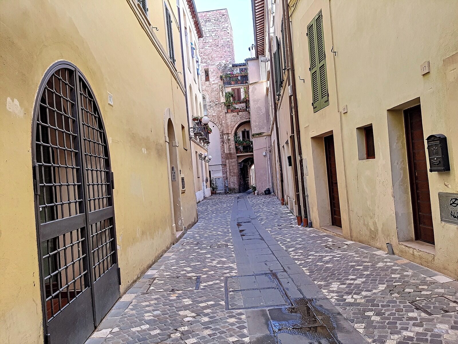 Una estrecha calle adoquinada bordeada por edificios con puertas ojivales y rejas.