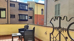 Een balkon met rieten meubilair, een stenen bank en een metalen poort.