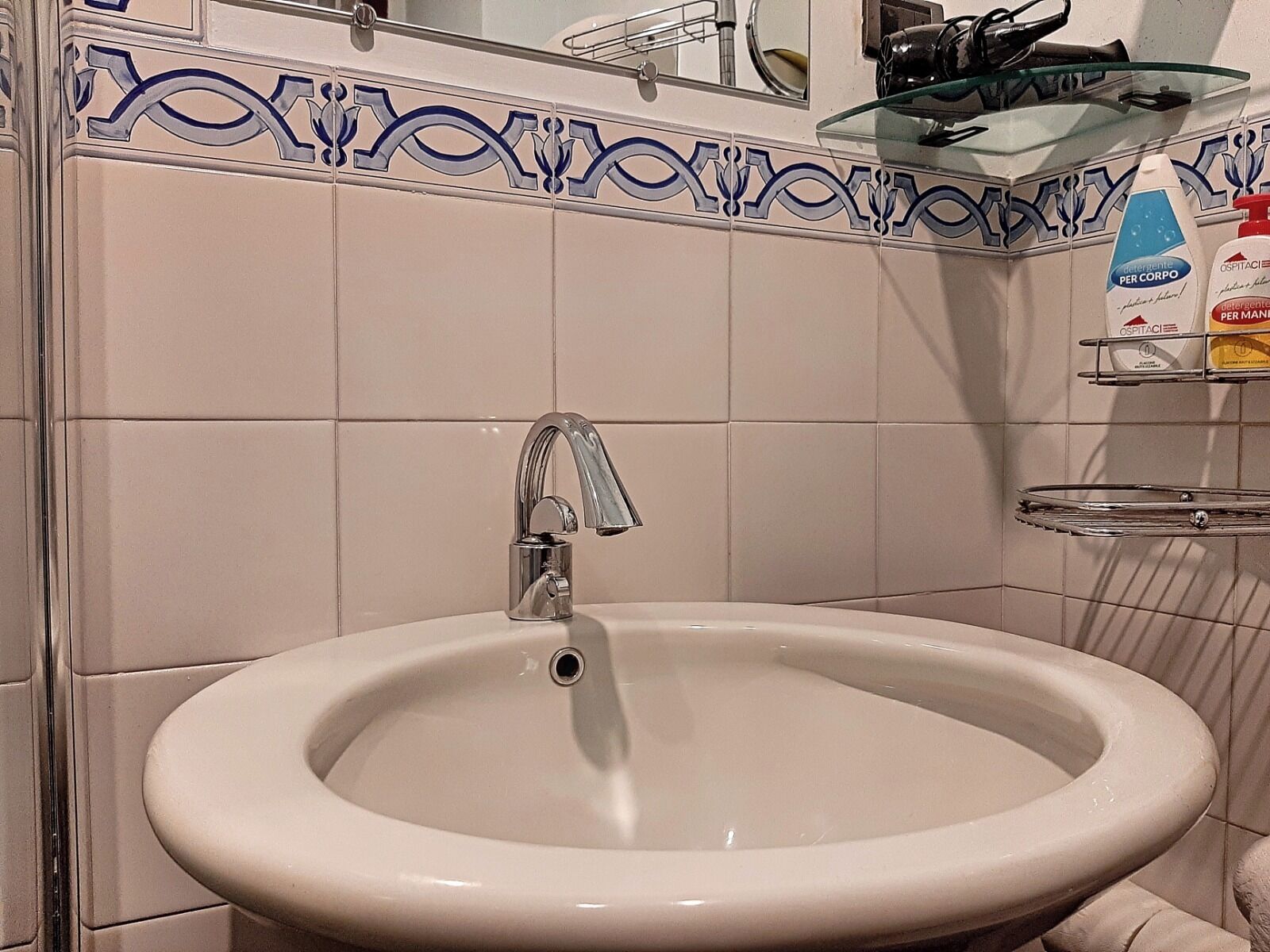 Un baño con un lavamanos blanco, un grifo cromado y un borde decorativo de azulejos.