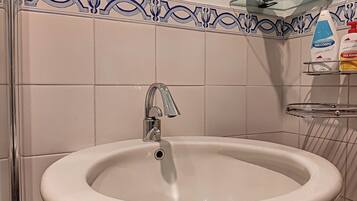 Un baño con un lavamanos blanco, un grifo cromado y un borde decorativo de azulejos.