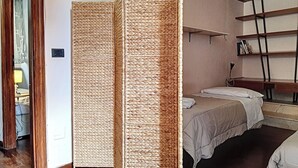 Een kamer met een bed, een bureau en een plank.