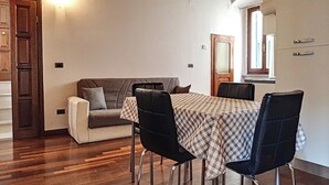 Een eetgedeelte met een tafel voor vier personen, een bank en een houten trap.