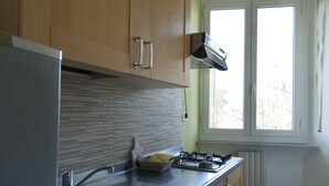 Een keuken met roestvrijstalen apparatuur, houten kasten en een raam met uitzicht op bomen.