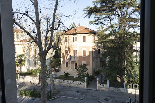 A multi-story building with a brick facade, multiple windows, and a small balcony.