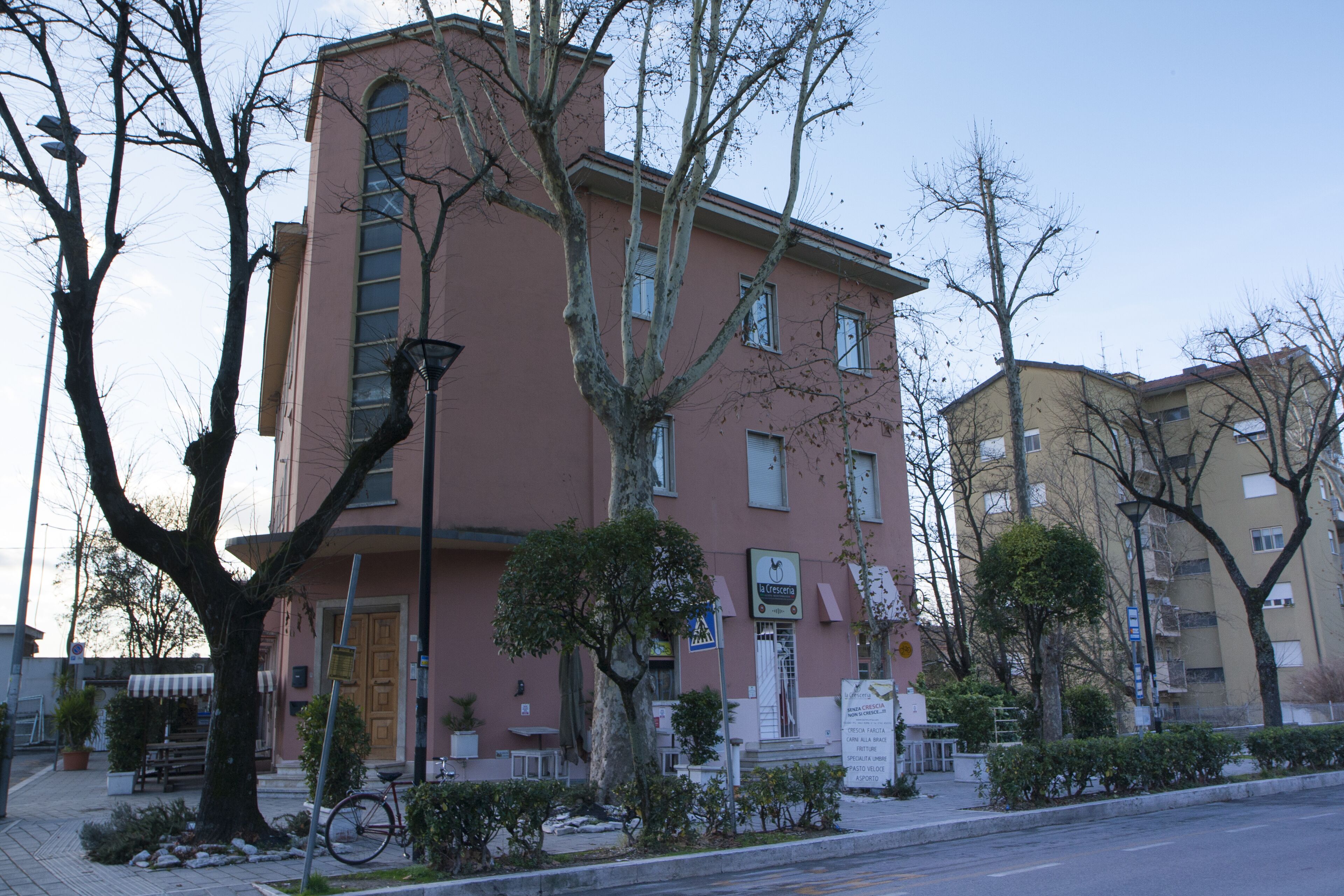 Un immeuble à plusieurs étages, doté d’une façade rose, d’une entrée bien visible et d’une enseigne indiquant qu’il s’agit d’un établissement commercial.
