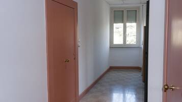 Ein Flur mit einer geschlossenen Tür links und einem Fenster rechts.