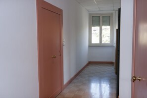 Ein Flur mit einer geschlossenen Tür links und einem Fenster rechts.