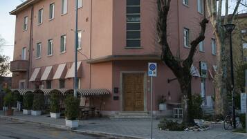 Un edificio rosa con ingresso centrale, posti a sedere all'aperto e un segnale che indica divieto di parcheggio.
