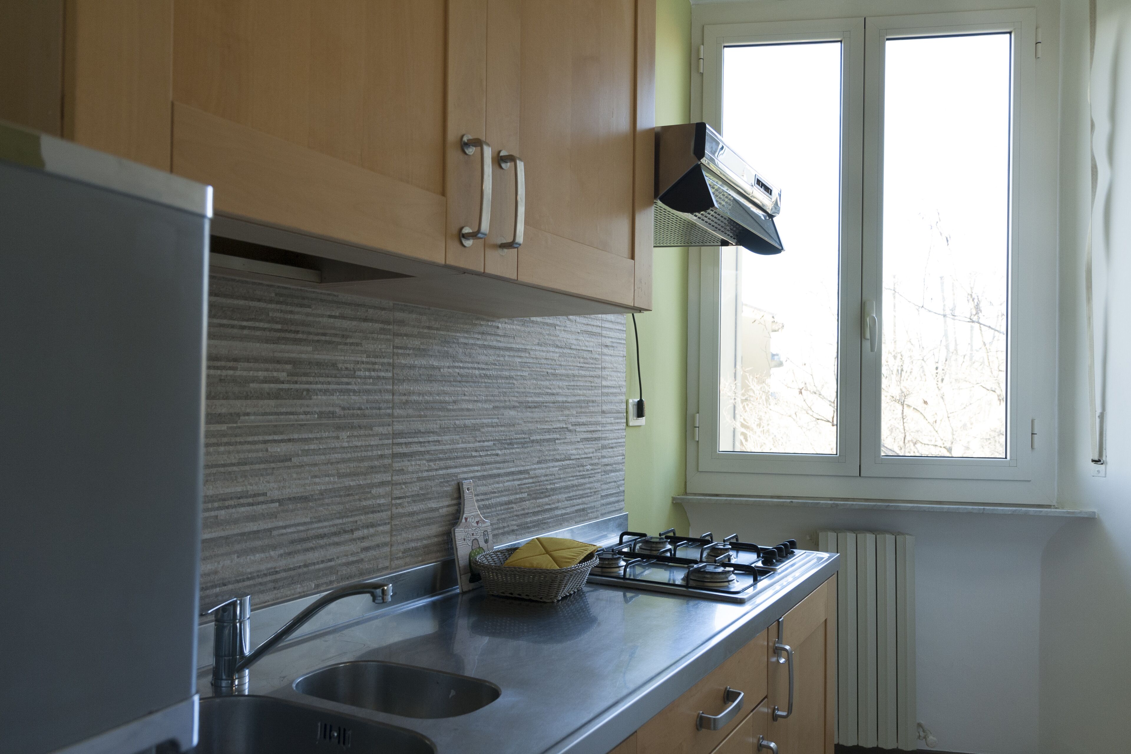 Eine Küche mit Edelstahlgeräten, Holzschränken und einem Fenster mit Blick auf Bäume.