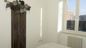 Una camera da letto con un letto, un armadio in legno e una finestra vista edifici.