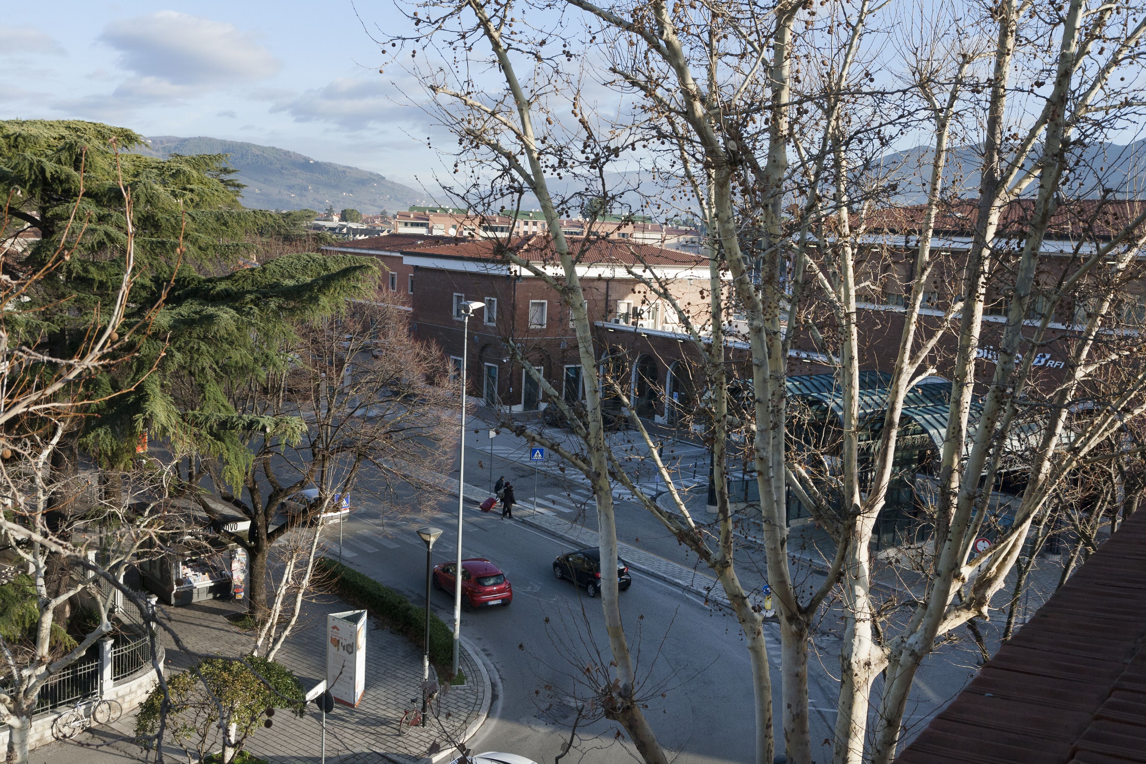 Une vue de rue avec des bâtiments, des arbres et des voitures garées.