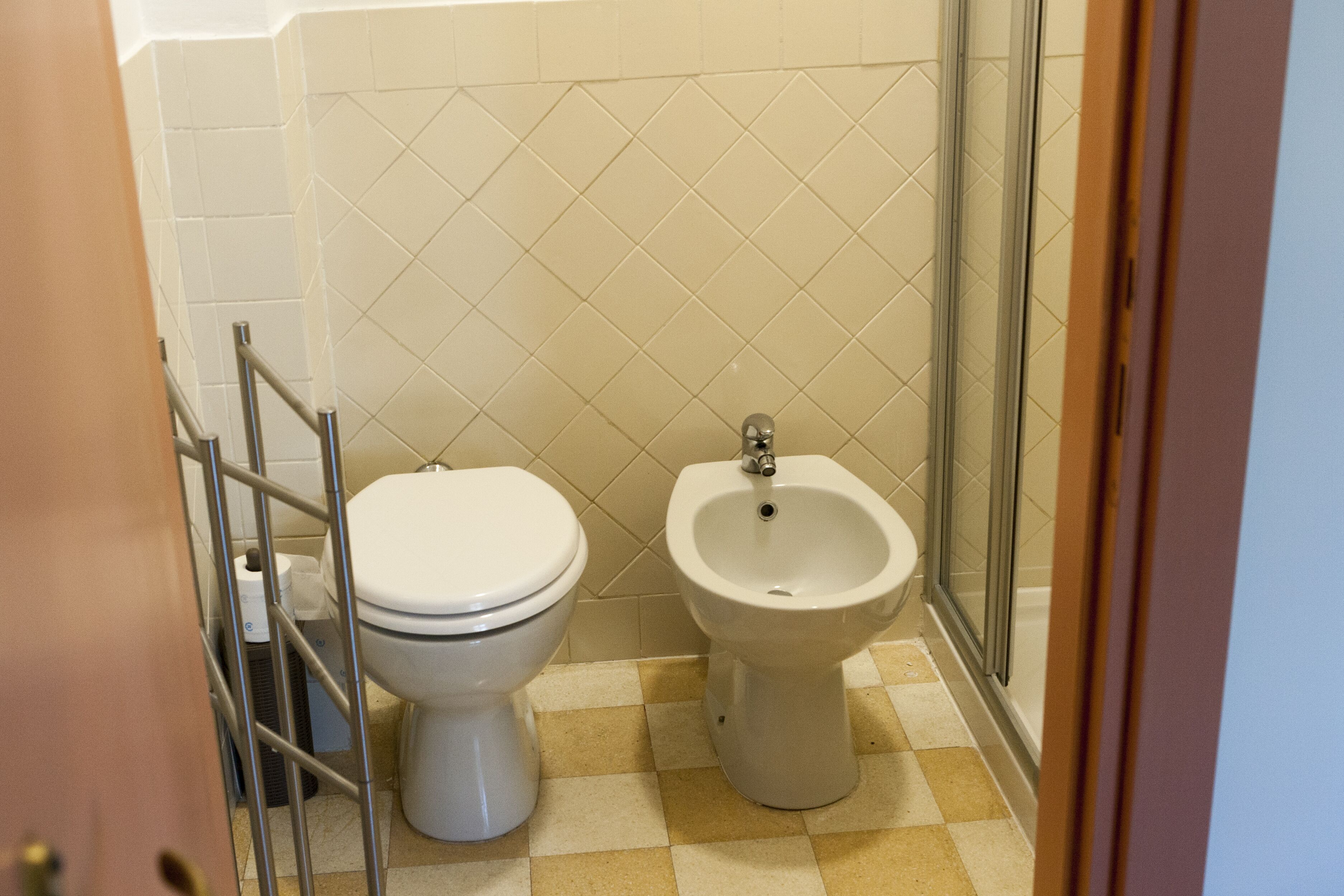 Ein Badezimmer mit Toilette, Bidet und Duschkabine aus Glas.