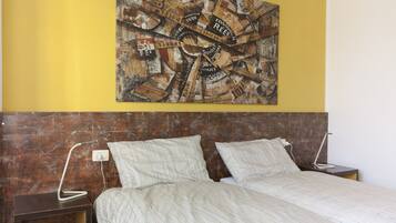 A bedroom with a bed, two bedside tables, a wall-mounted artwork, and a wooden headboard.