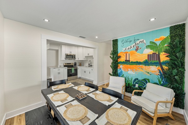 The modern dining area features sleek chairs and a minimalist table, perfect for comfort and connection. A striking mural by a local artist showcases Lakeland’s iconic lakes, landmarks, and downtown, adding a vibrant, personal touch.
