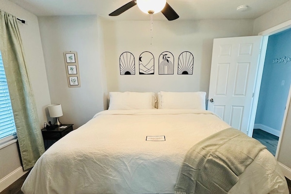 Unwind in this cozy master bedroom featuring a plush king-size bed with soft bamboo sheets, a cotton comforter, and warm, inviting décor. A 40" Roku TV provides access to your favorite apps along with complimentary Netflix and Roku TV.