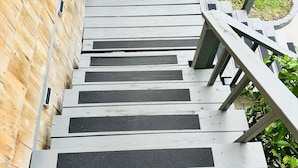 Een houten trap met metalen leuning die uitkomt op een houten terras.