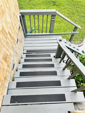 Una escalera de madera con barandilla de metal que conduce a una terraza de madera.