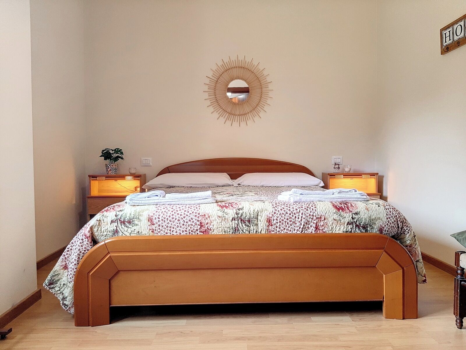 A bedroom with a wooden bed, a round mirror on the wall, and two bedside tables with lamps.