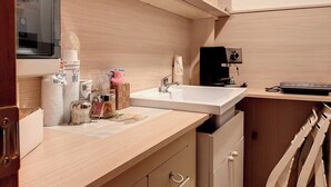 Una cocina compacta equipada con microondas, lavamanos y cafetera.