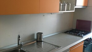 A kitchen with stainless steel appliances, a sink, and orange cabinets. - Via Oberdan 113 by Ospitaci (Foligno)