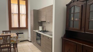 A compact kitchen with wooden cabinets, a gas stove, and a dining area with a table and chairs.