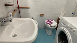 A bathroom with a sink, toilet, and washing machine.
