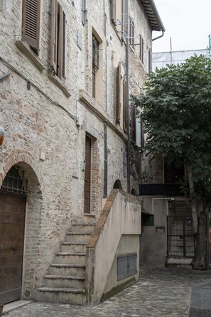 A narrow stone building with a staircase leading to an upper level.
