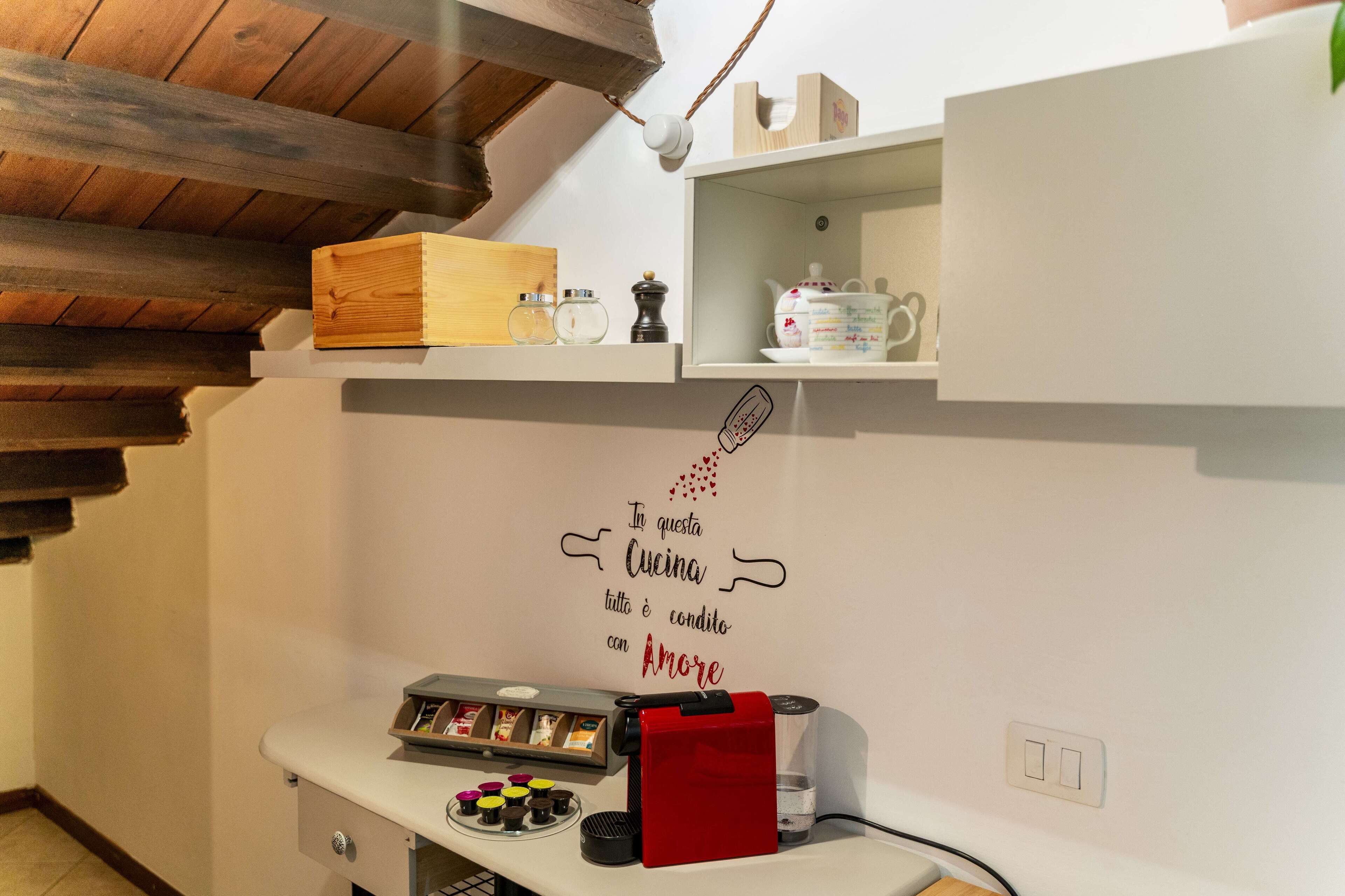 A kitchen with wooden beams, a coffee machine, a kettle, and a shelf with kitchenware.