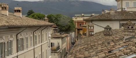 A historic town with terracotta-tiled roofs, traditional architecture, and a mountain in the background.