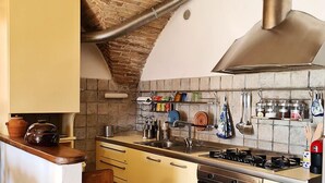 A compact kitchen with a brick ceiling, a gas stove, an oven, and a sink.