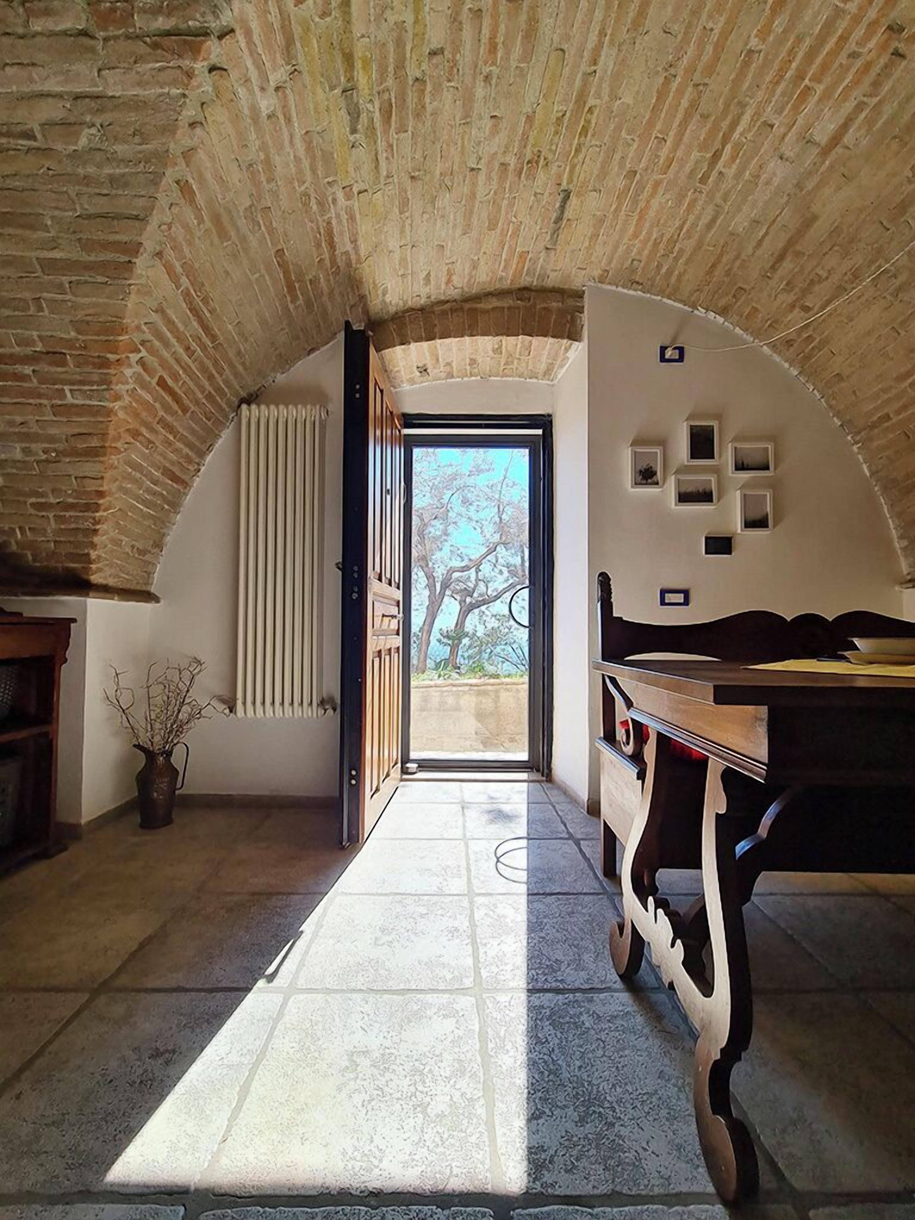 Um quarto em arco com vista para o exterior, um radiador e uma mesa de madeira.