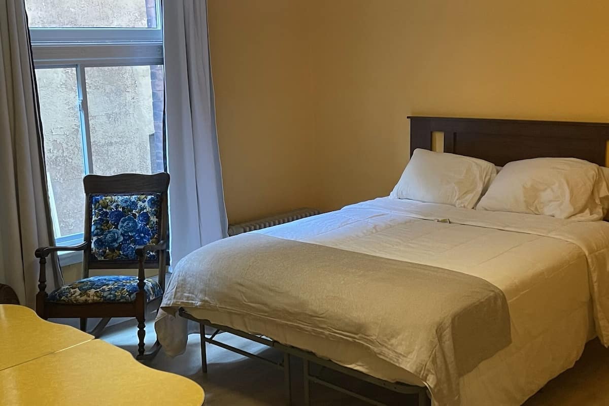 A bedroom with a bed, a chair, and a table.