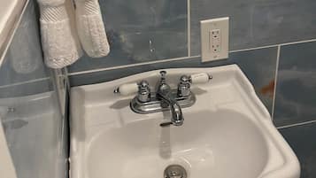 A bathroom with a white sink, a towel rack, a mirror, and blue-tiled walls.